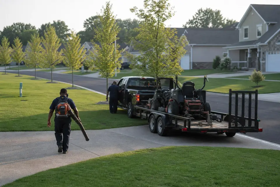 Landscaping truck and trailer parked on a curving subdivision street
