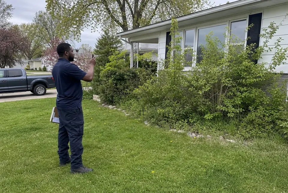 Worker photographing overgrown shrubs to price the job
