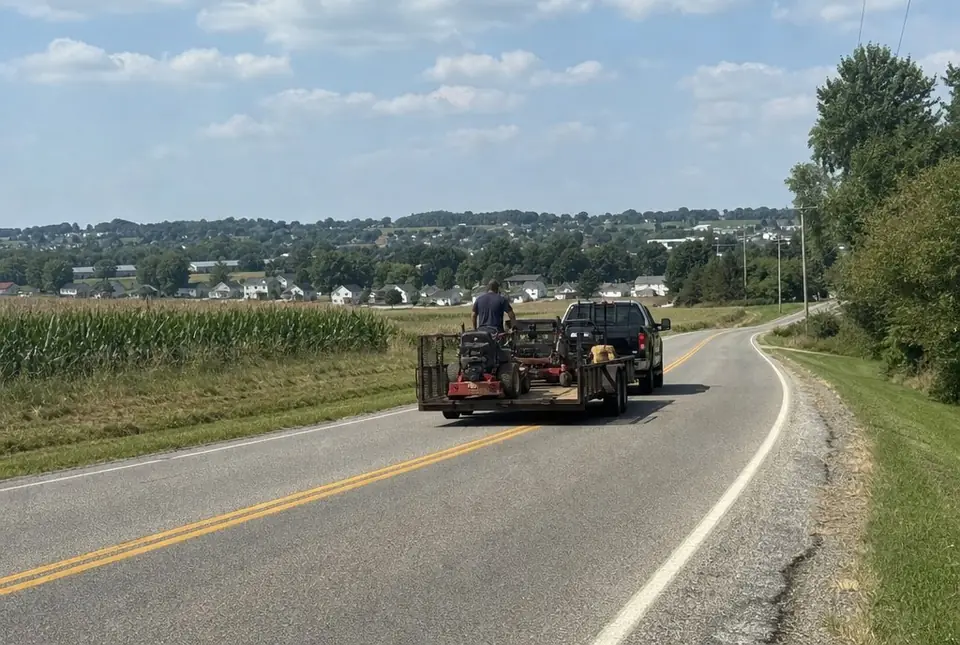 Pickup towing a landscape trailer along a country road