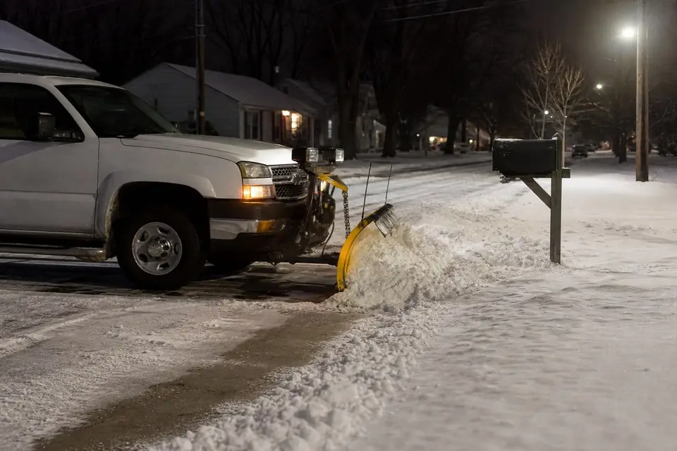 Plow blade pushing snow into a neat bank beside a mailbox