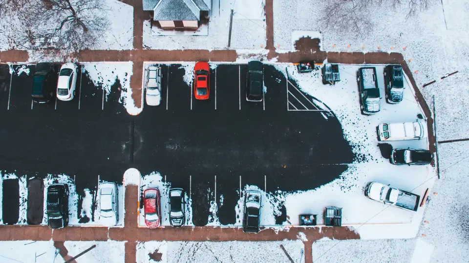 Aerial view of a plowed parking lot with snow pushed to the edges